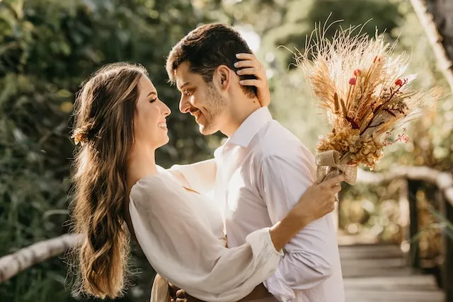 Honeymoon Suites Houston: Memorable Things to Do for Newlyweds. A man in a white dress shirt holds a bouquet of brown flowers.